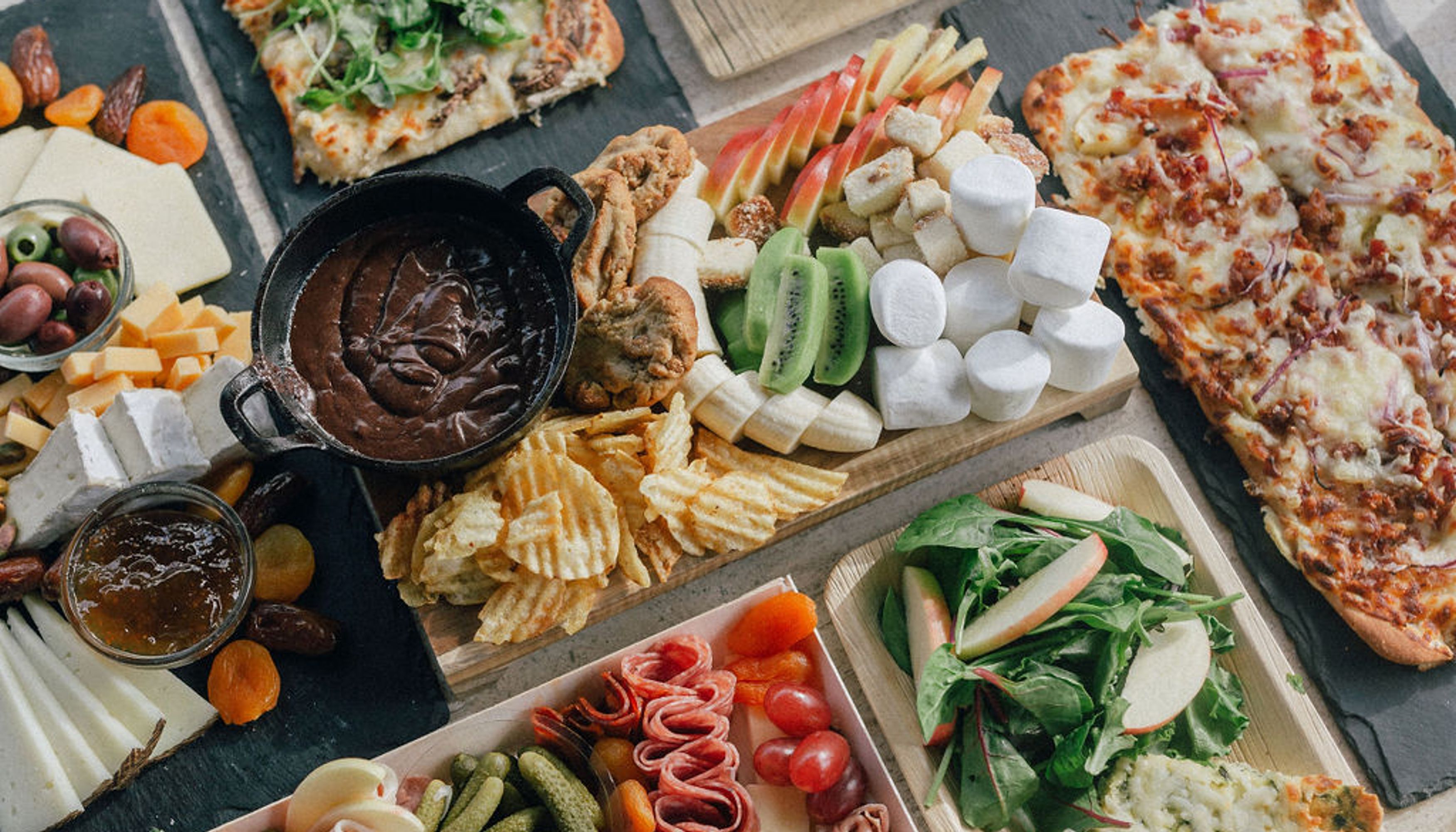 Charcuterie board filled with veggies, flatbreads, fruits, and meatsundefined