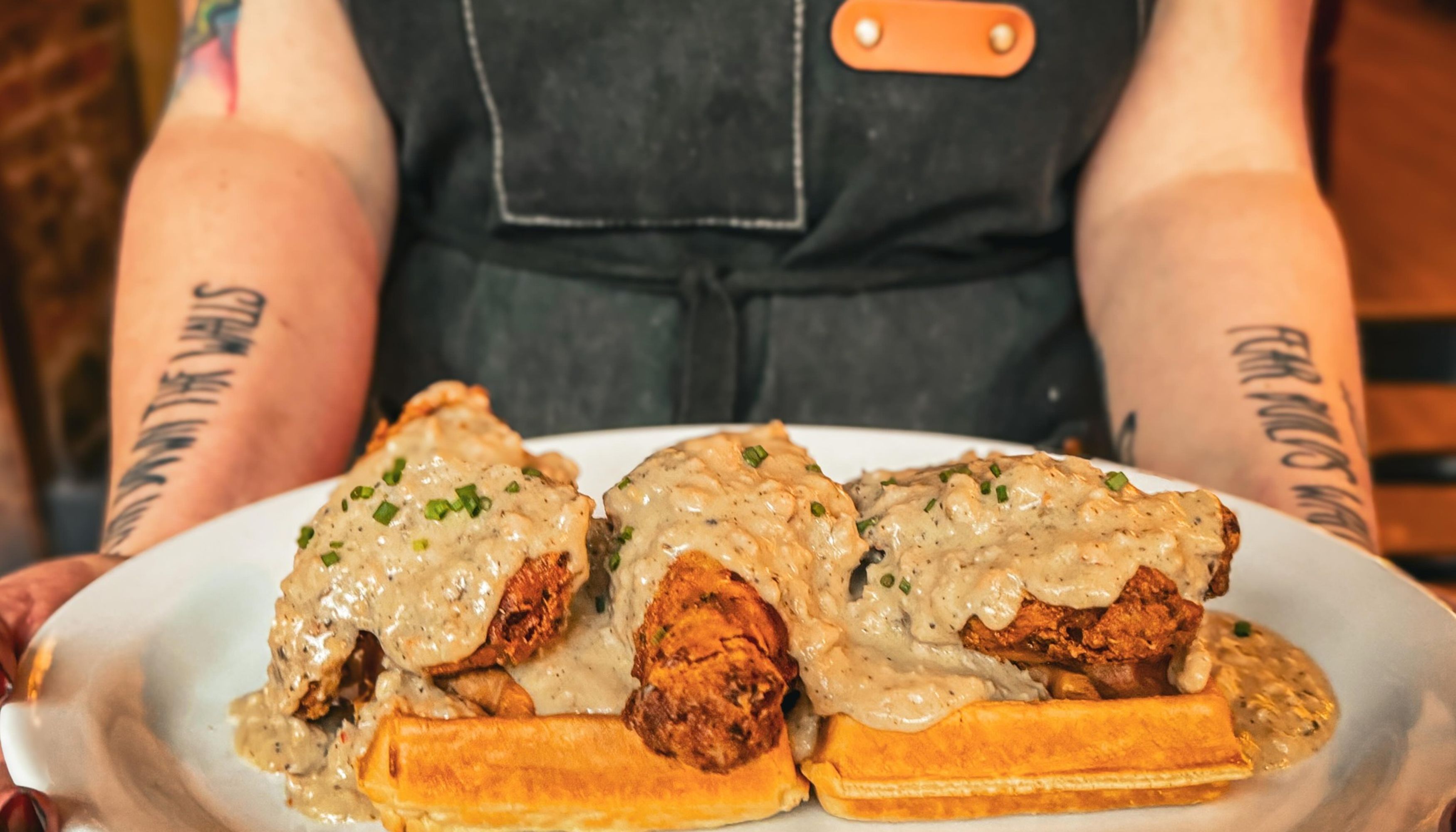 fried chicken and waffles on a plate held by waitressundefined