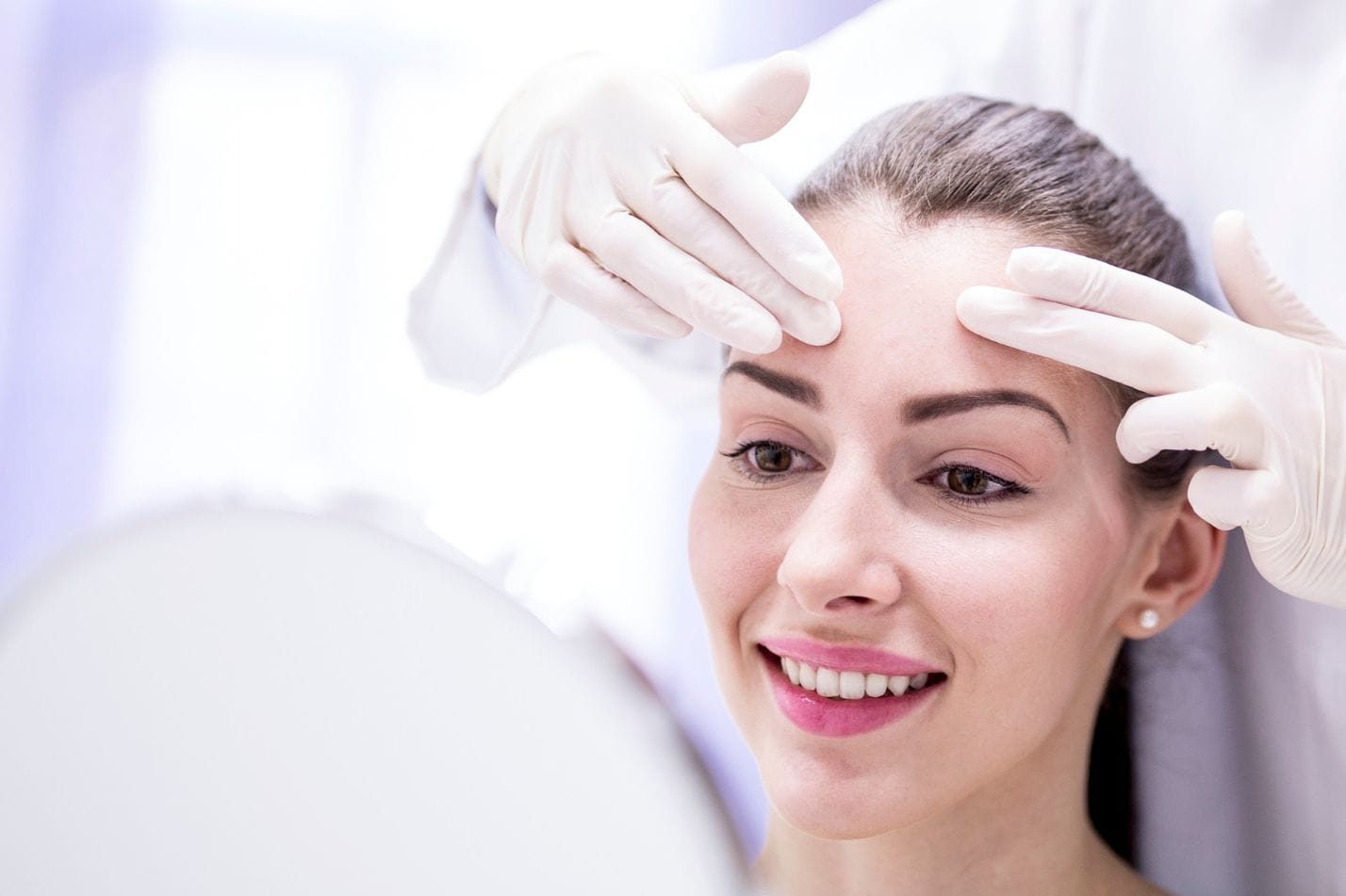 Woman smiling during a forehead treatment