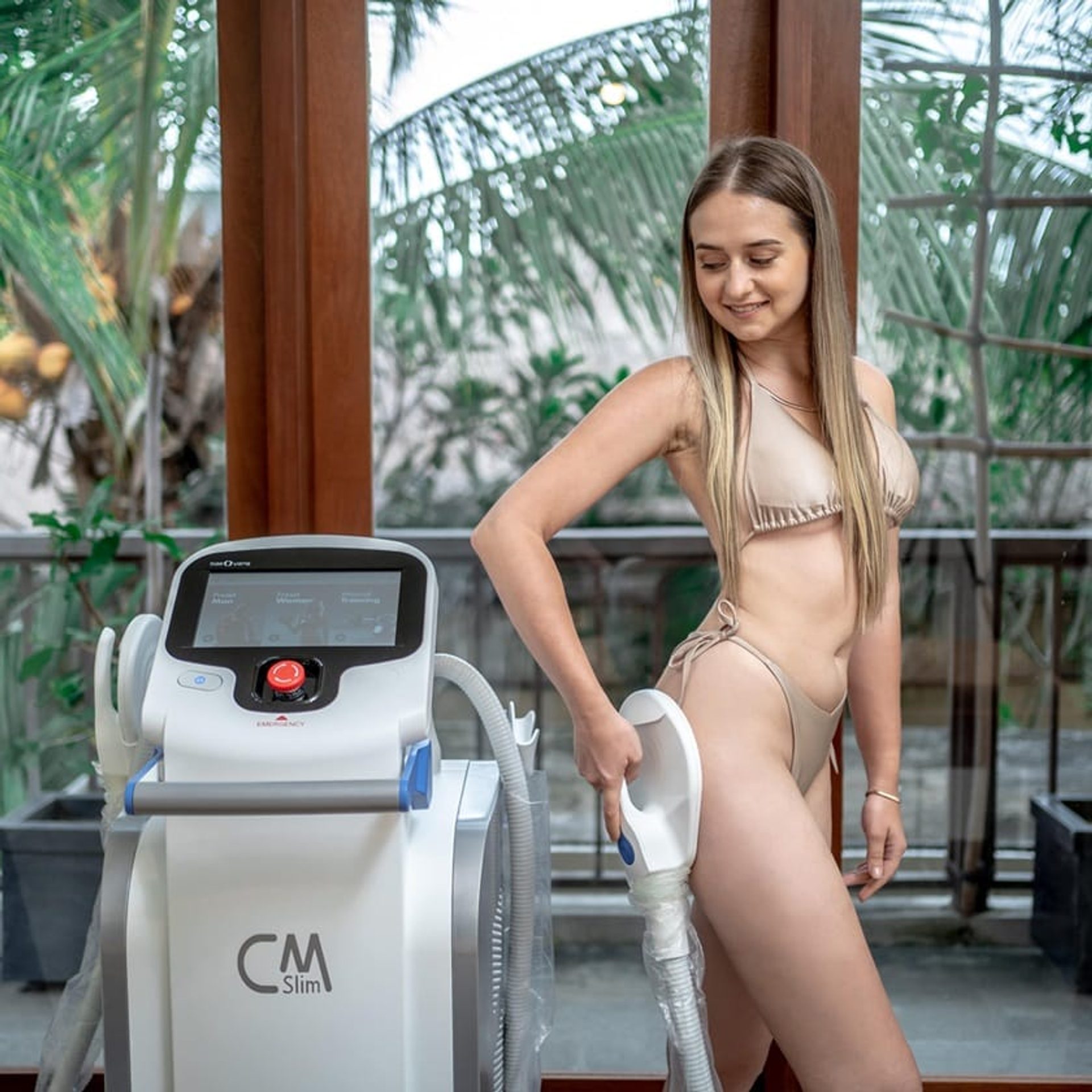 A woman standing beside the CM Slim muscle sculpting device