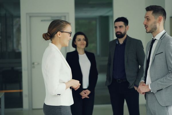 Business professionals conversing in a modern office hallway.