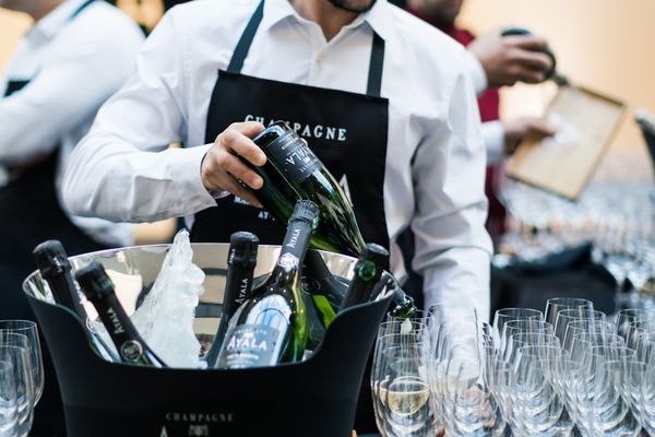 a man holding a bottle of wine in a bucket filled with wine glasses