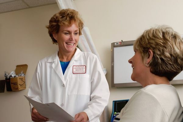 woman in white scrub suit holding gray laptop computer