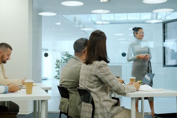 Woman presenting to colleagues in a modern office meeting.