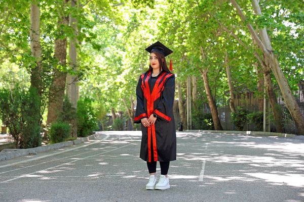 Young woman in graduation gown standing outdoors