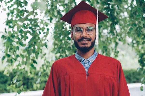 A smiling graduate in a red cap and gown.