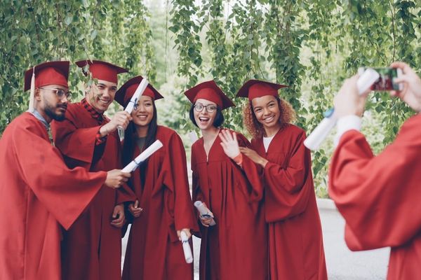 Graduates in red robes pose for a photo outdoors