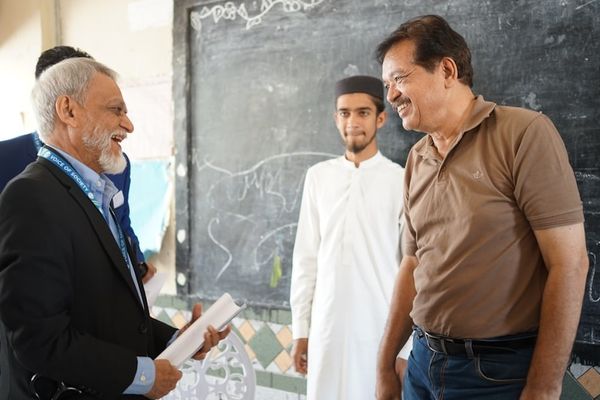 Two men talking in front of a chalkboard.