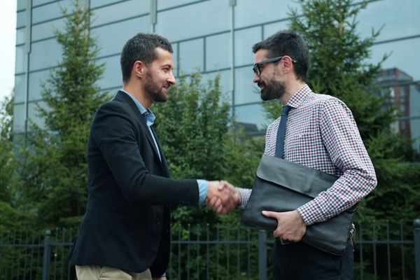 Two businessmen shaking hands outside modern building