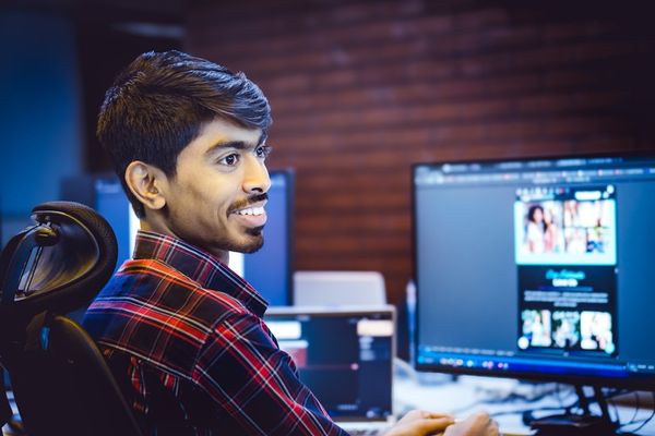A man smiles while working at his computer.
