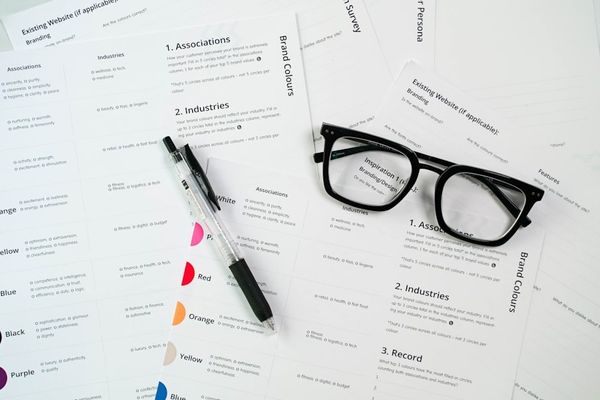 a pair of glasses sitting on top of a pile of paper