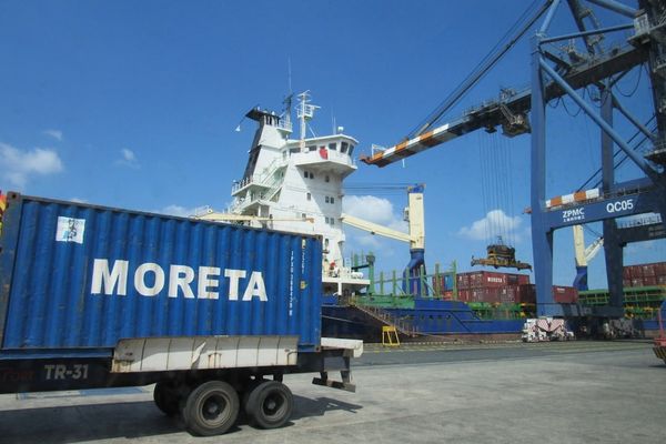 A large cargo ship is being loaded at a port.