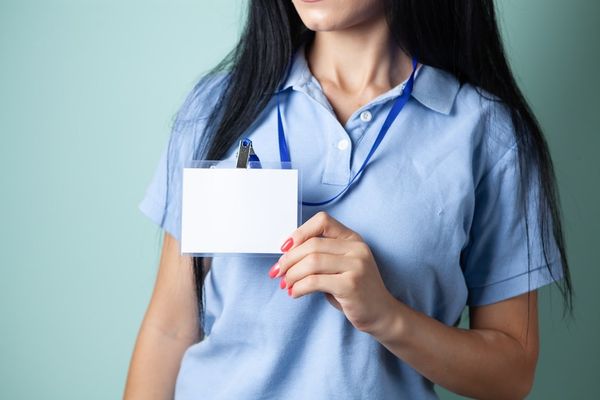 Woman in blue shirt holding blank white id badge