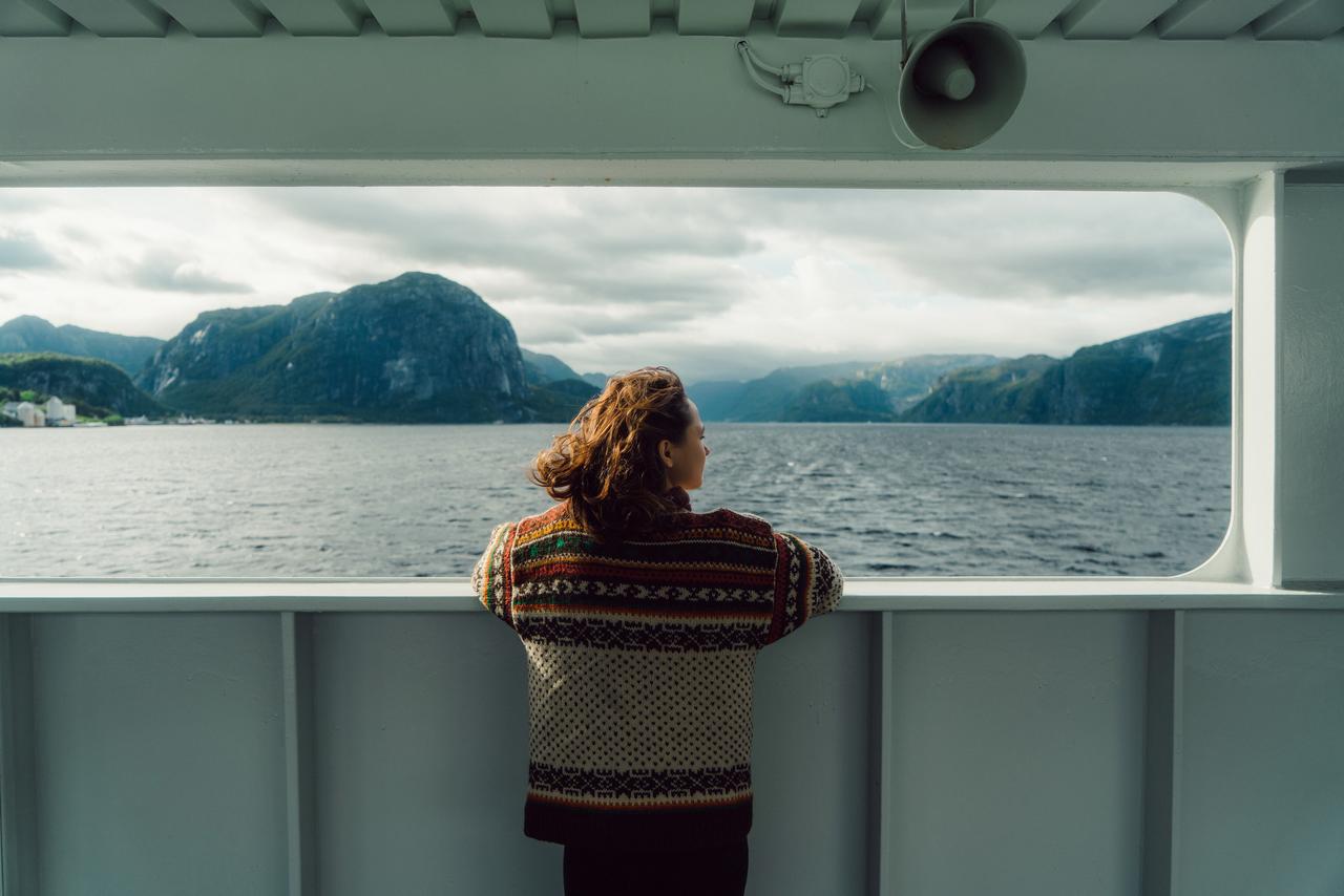 Frau steht auf Fähre und schaut auf Fjord