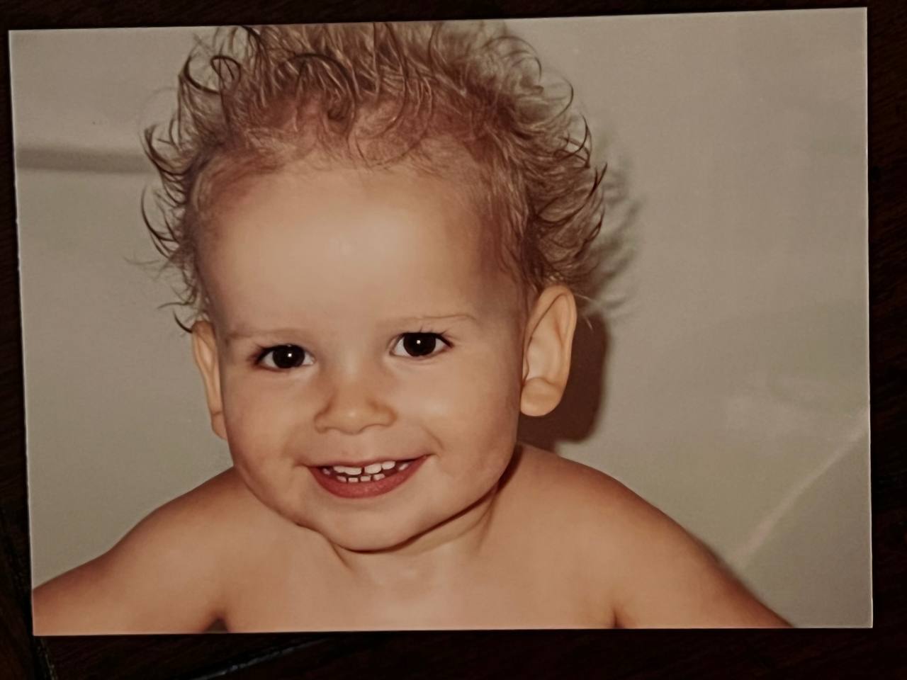 Childhood portrait — wild curls and a wide grin.
