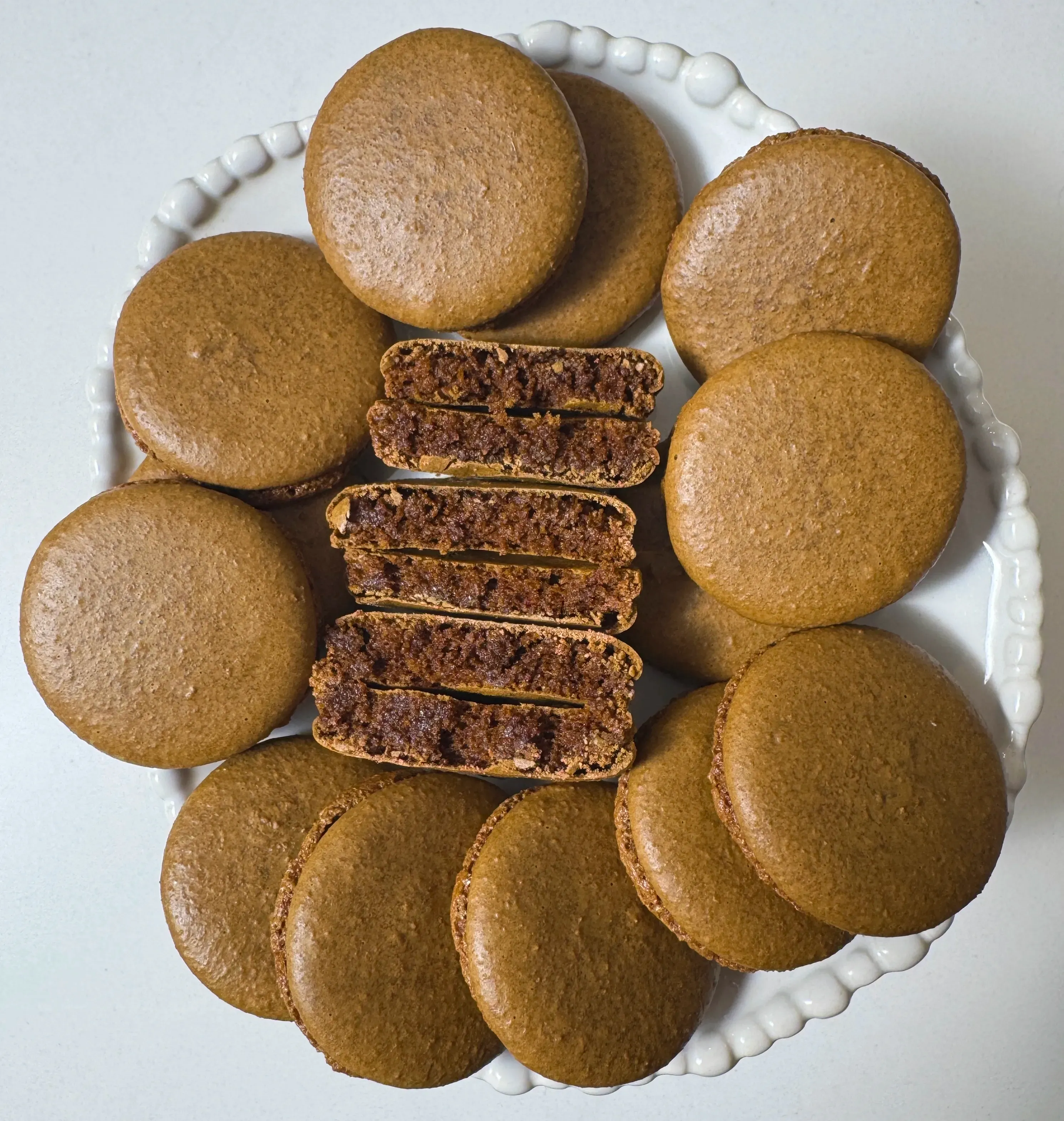 Plate of chocolate brown macaron shells arranged on a porcelain footed pastry stand