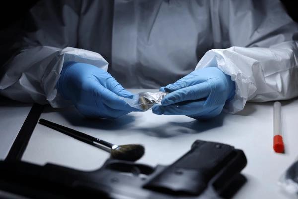 Forensic examiner handling recovered ballistic evidence in a crime lab