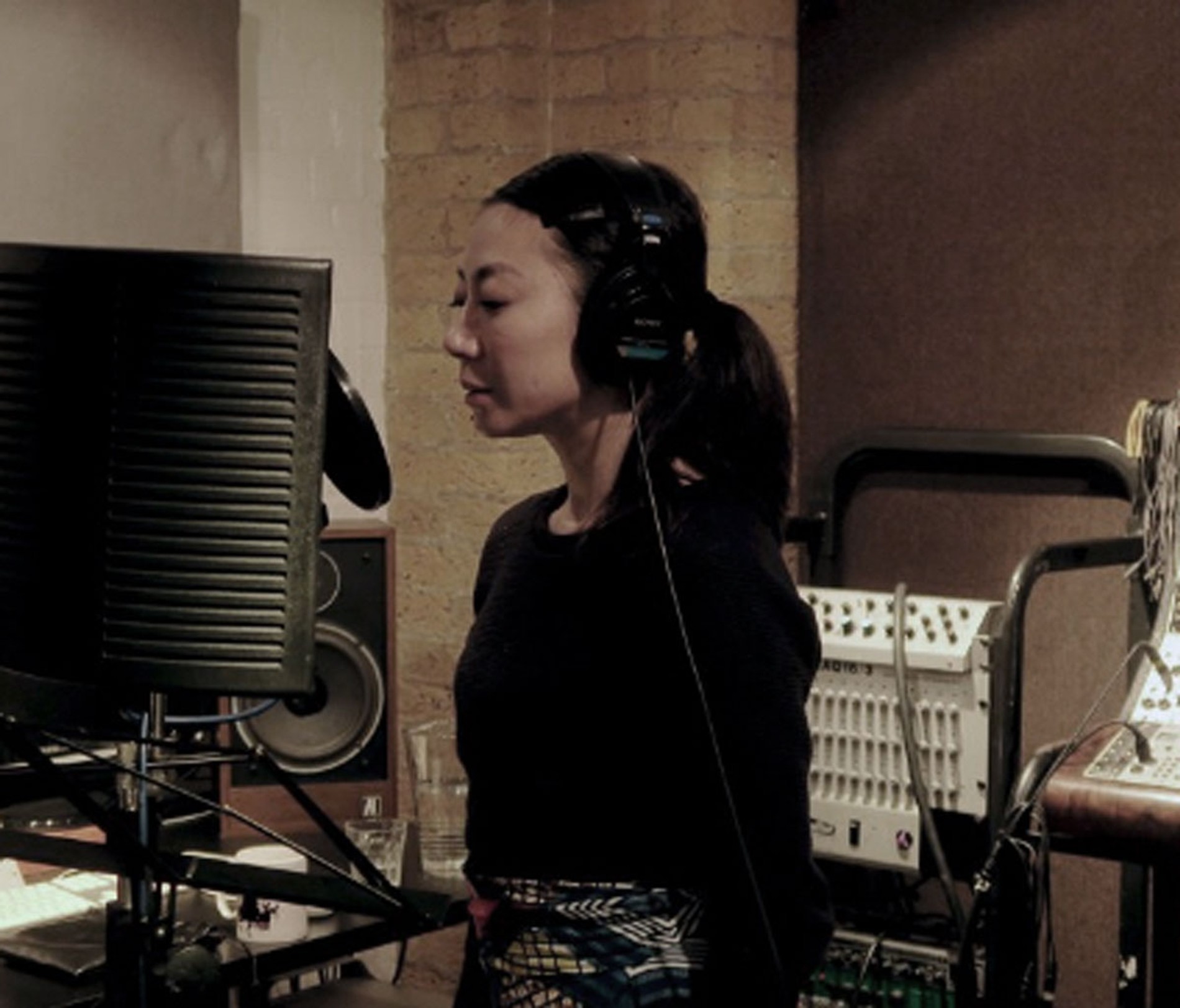 A person stands and speaks into a microphone in a studio, they're recording ADR at Coda to Coda