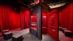 Image showing the CHORUS installation booth, a metal structure with a microphone for recording a voice, surrounded by red velvet curtain, with installation composition and programming by Coda to Coda at at the Wellcome Collection.