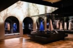 Image shows a view of the gallery, The Expression Of A Stark Luxury , with a blue and pink dress on display. The scene design reference's Chanel's house La Pausa. From Gabrielle Chanel. Fashion Manifesto at the V&A Museum London. Soundscape by Coda to Coda.