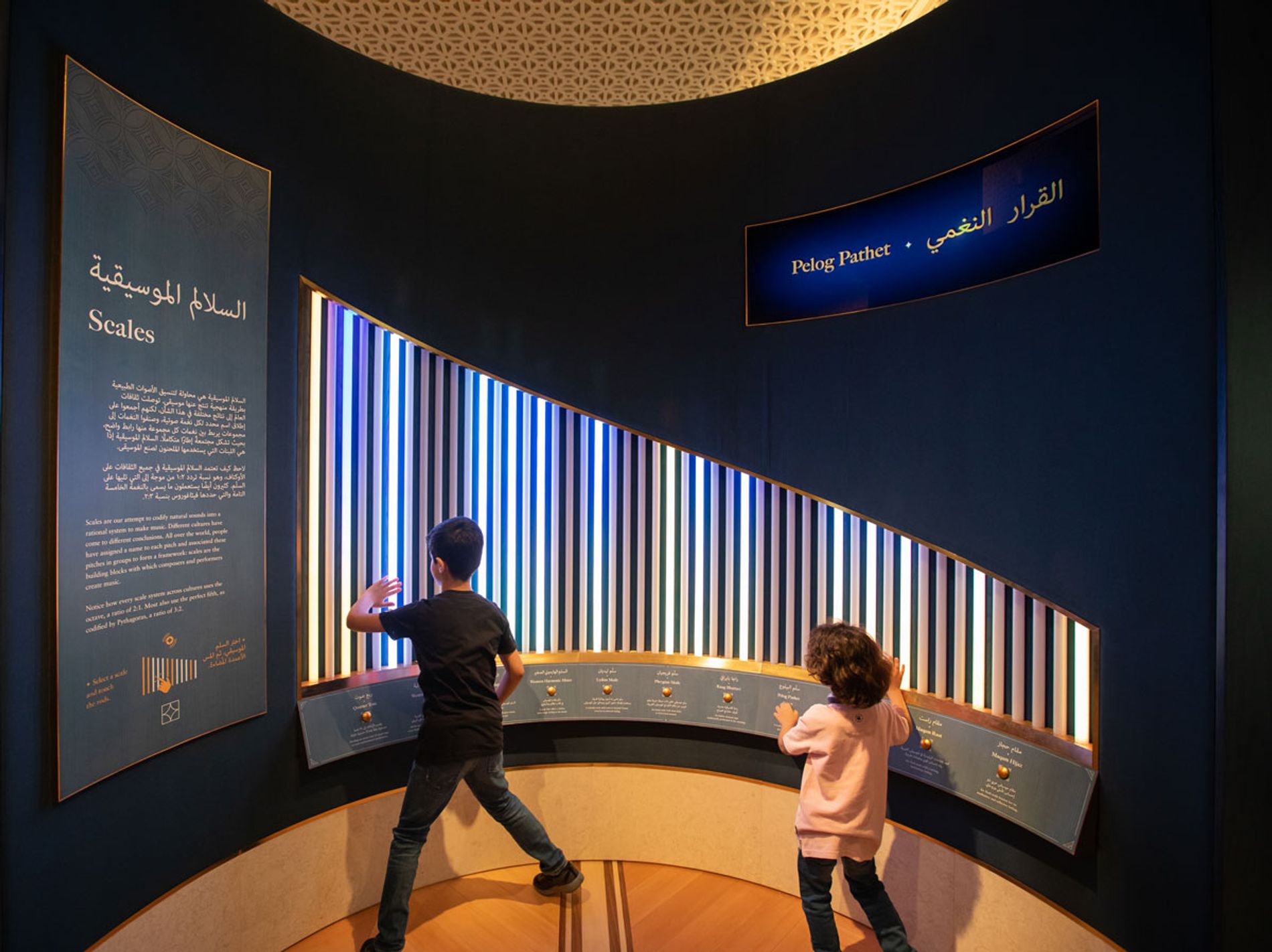 Image shows two children playing the interactive about Scales at Oman and the World: A Musical Journey in Muscat. Installation composer: Coda to Coda