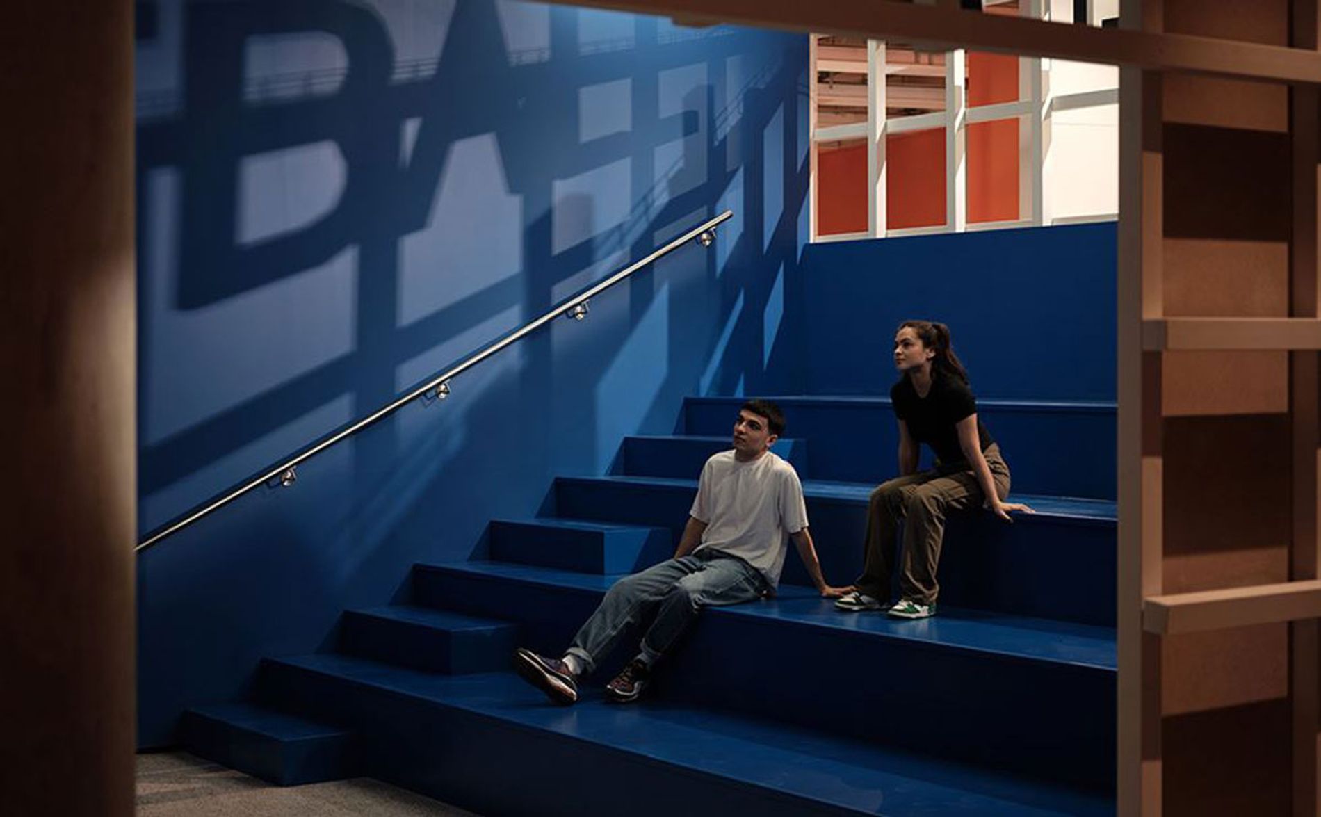 Two visitors in the Half time section of Football: Designing the Beautiful Game, listening to a soundscape by Coda to Coda at The Design Museum