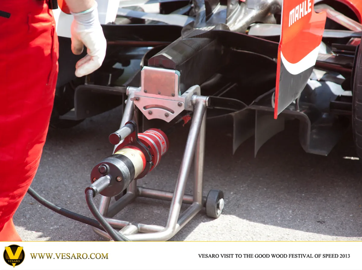 Rear of an F1 car in the Goodwood paddock with a mechanic and a starter jack at the gearbox