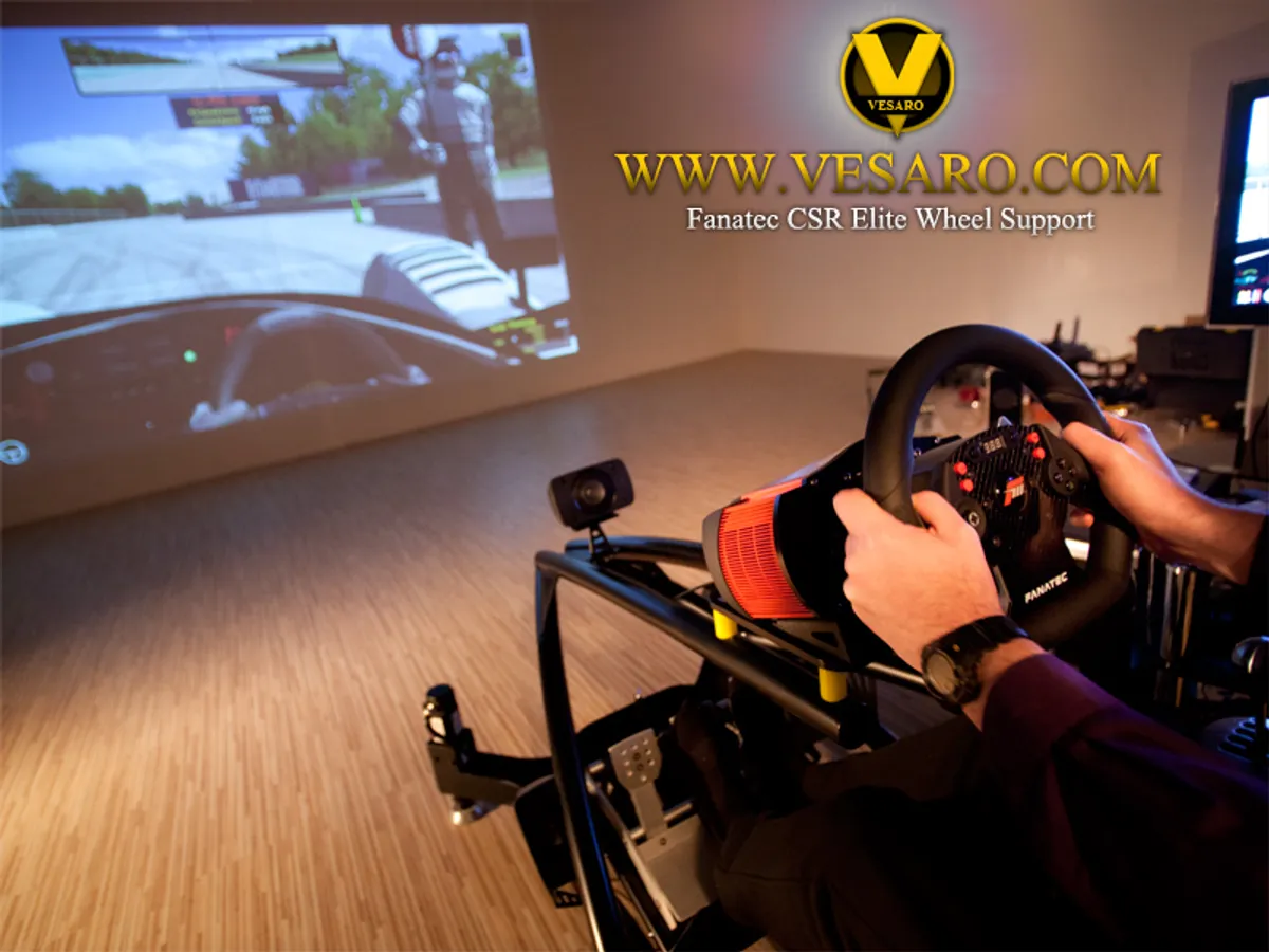 Hands on an orange and black Fanatec wheel mounted on a Vesaro rig facing a projected racing game screen