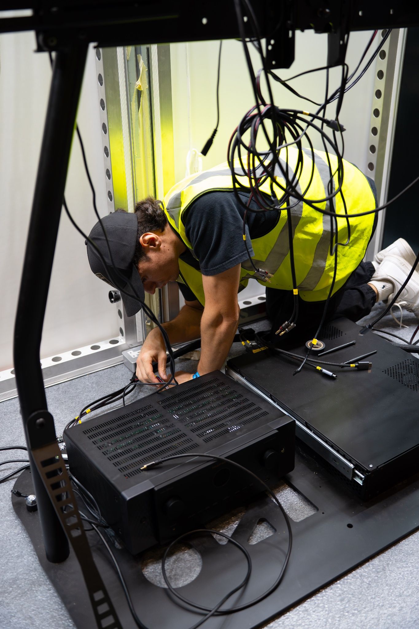Technician wiring hardware beneath a simulator during setup