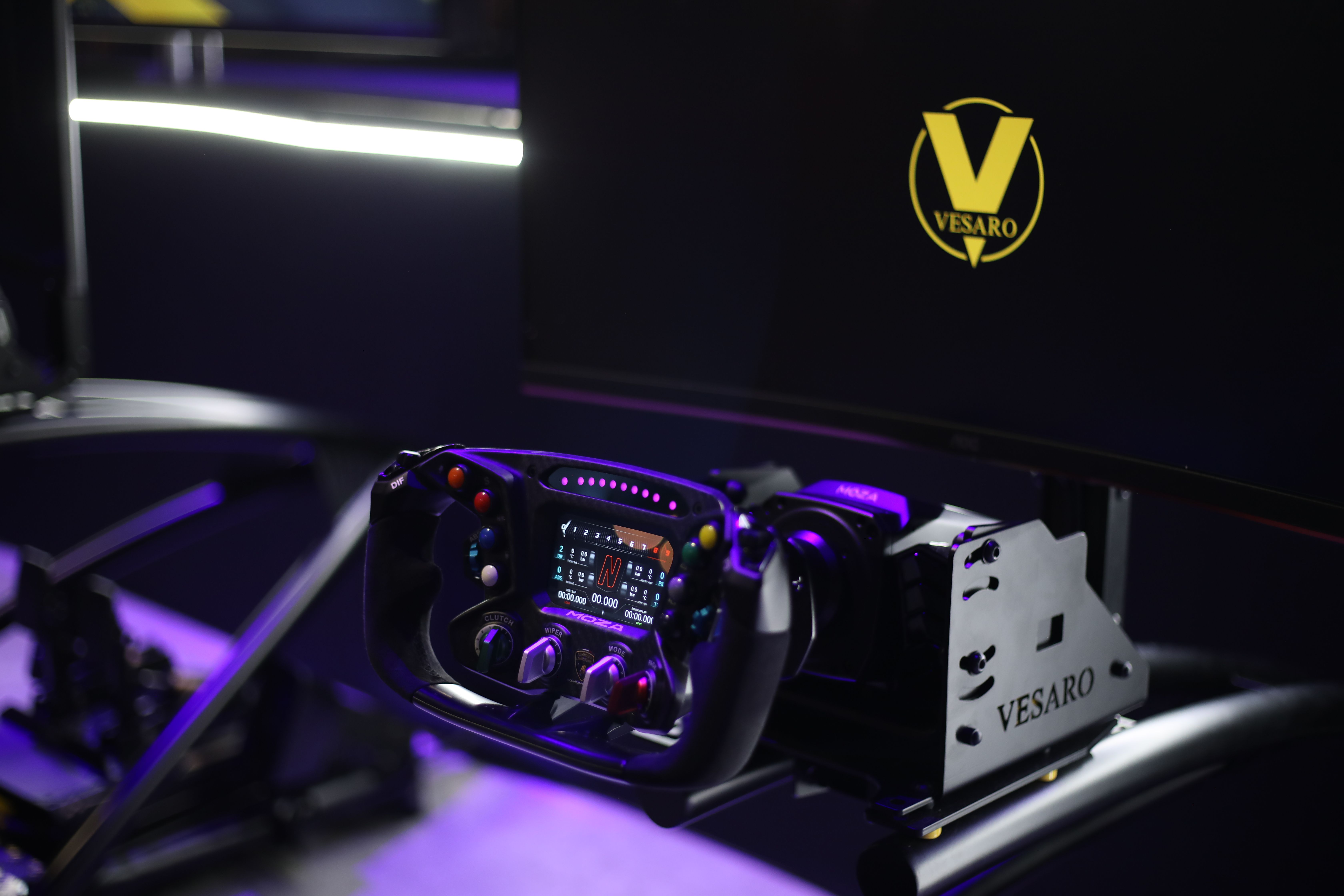 Formula-style steering wheel with a digital display mounted on a Vesaro rig in front of a black screen with the Vesaro logo