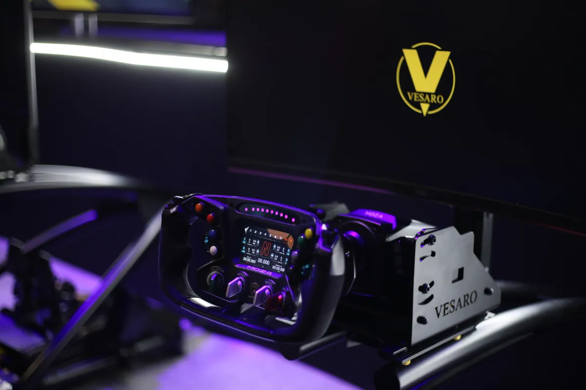 Formula-style steering wheel with a digital display mounted on a Vesaro rig in front of a black screen with the Vesaro logo