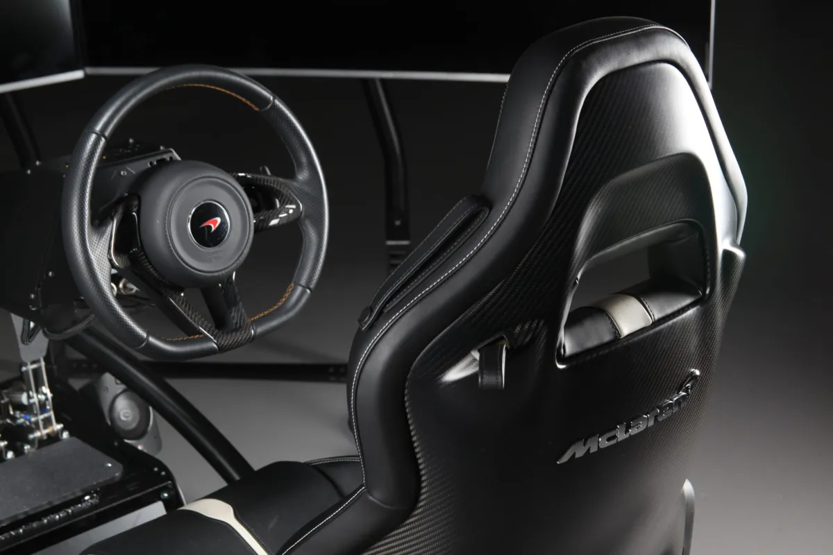 McLaren-branded bucket seat and steering wheel of a Vesaro simulator in low-key studio lighting