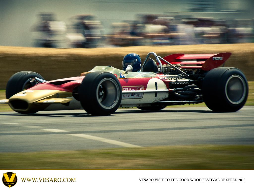 Vintage red, white and gold Lotus Formula 1 car at speed at the Goodwood Festival of Speed 2013
