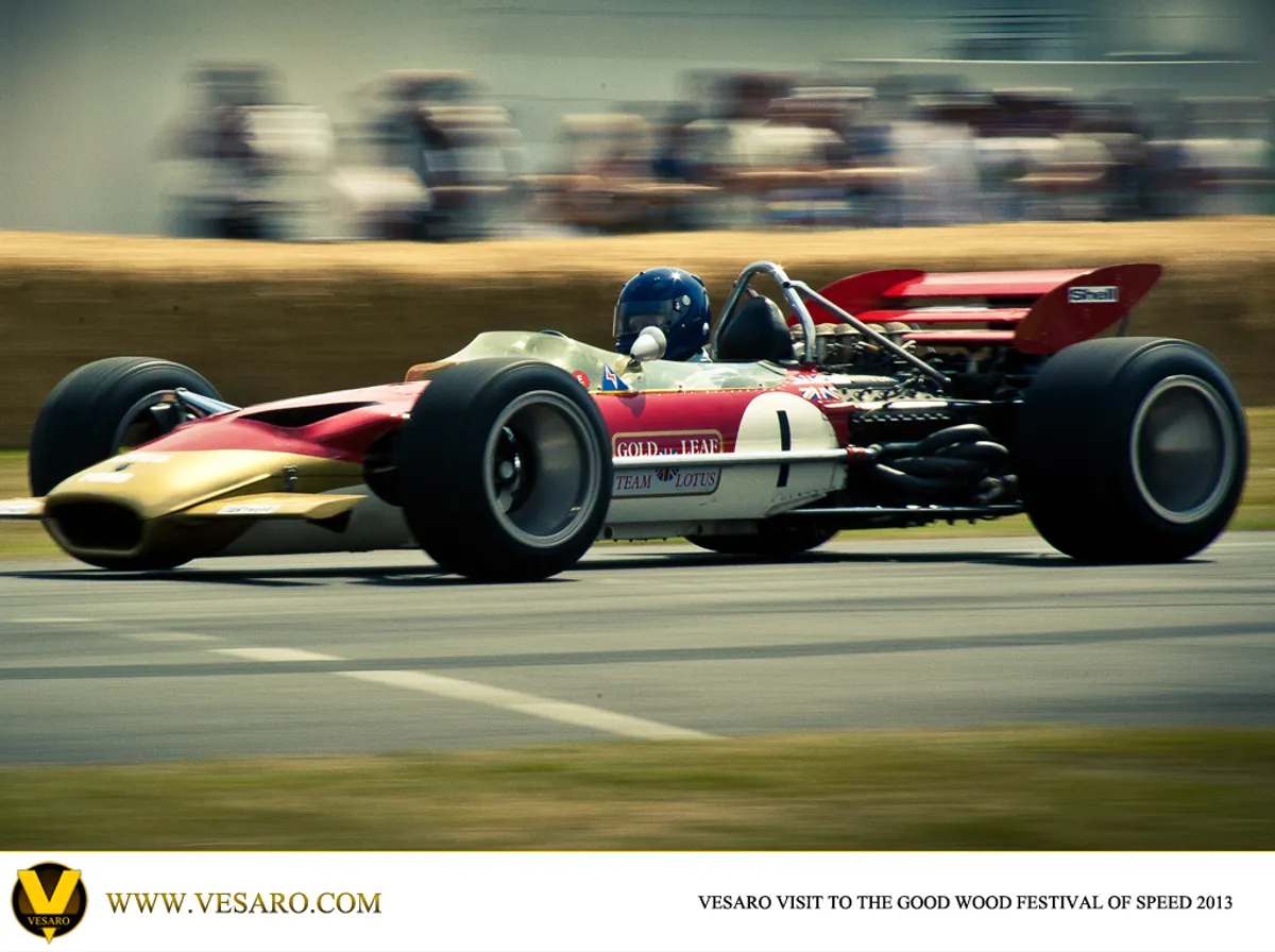 Vintage red, white and gold Lotus Formula 1 car at speed at the Goodwood Festival of Speed 2013