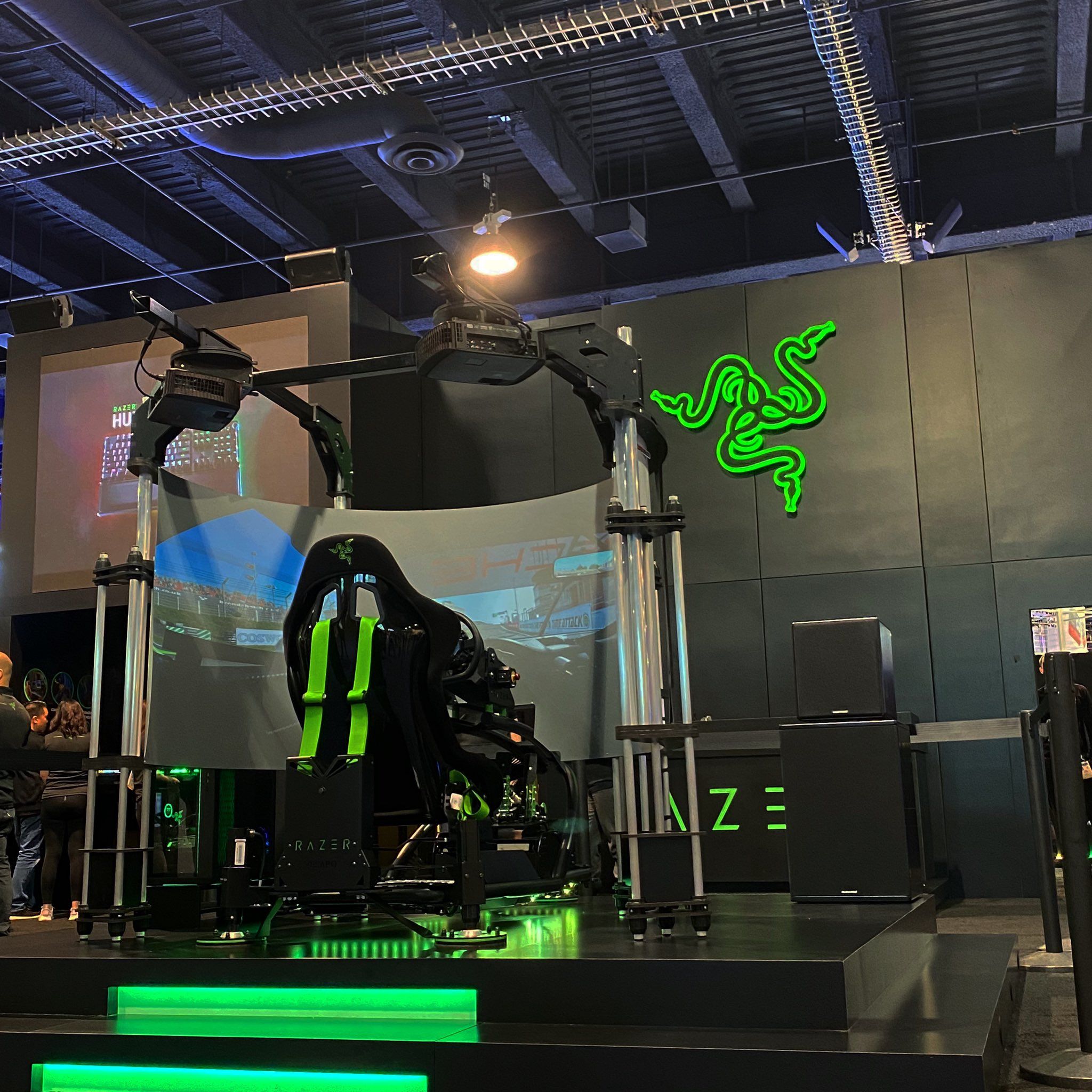 Razer motion simulator with wraparound screen on a lit stage at a trade show booth