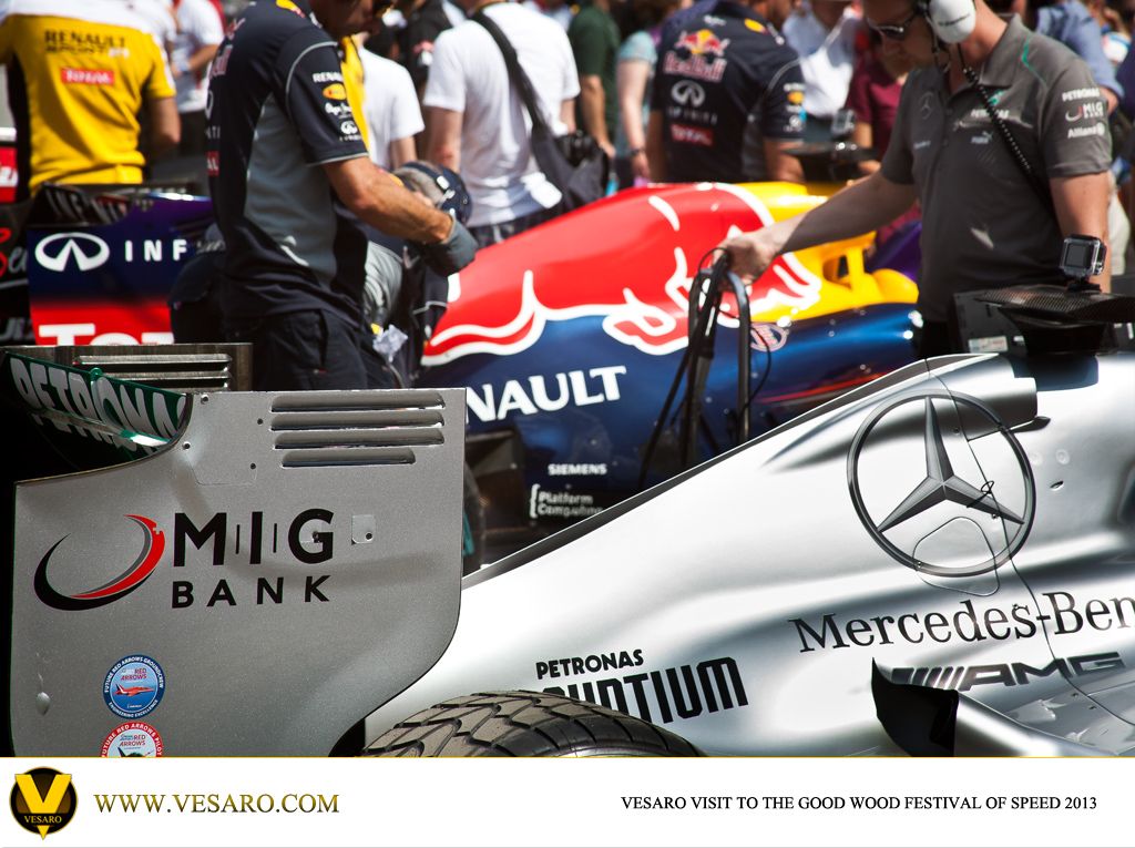 Mechanics at a Red Bull and Mercedes F1 car in the Goodwood paddock, MIG Bank sponsor logos visible