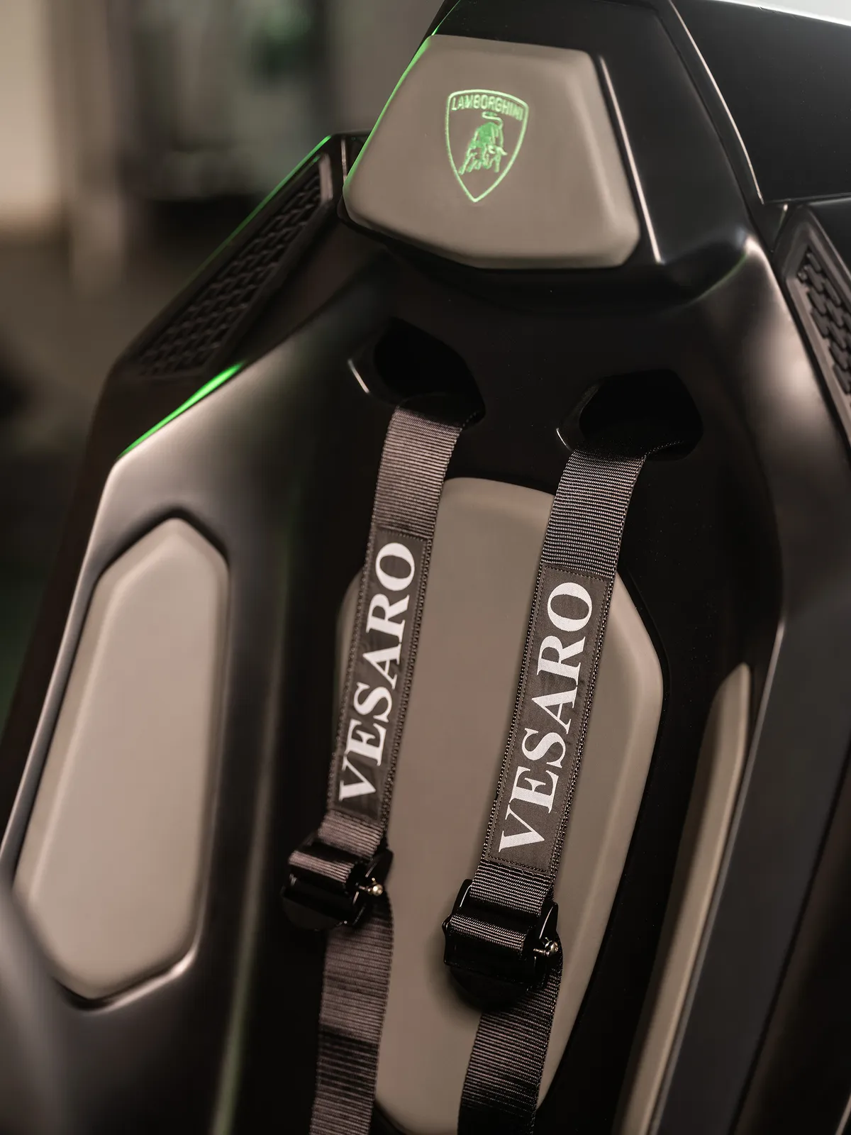 Black racing seat with Vesaro-branded harness straps and a green illuminated Lamborghini badge on the headrest
