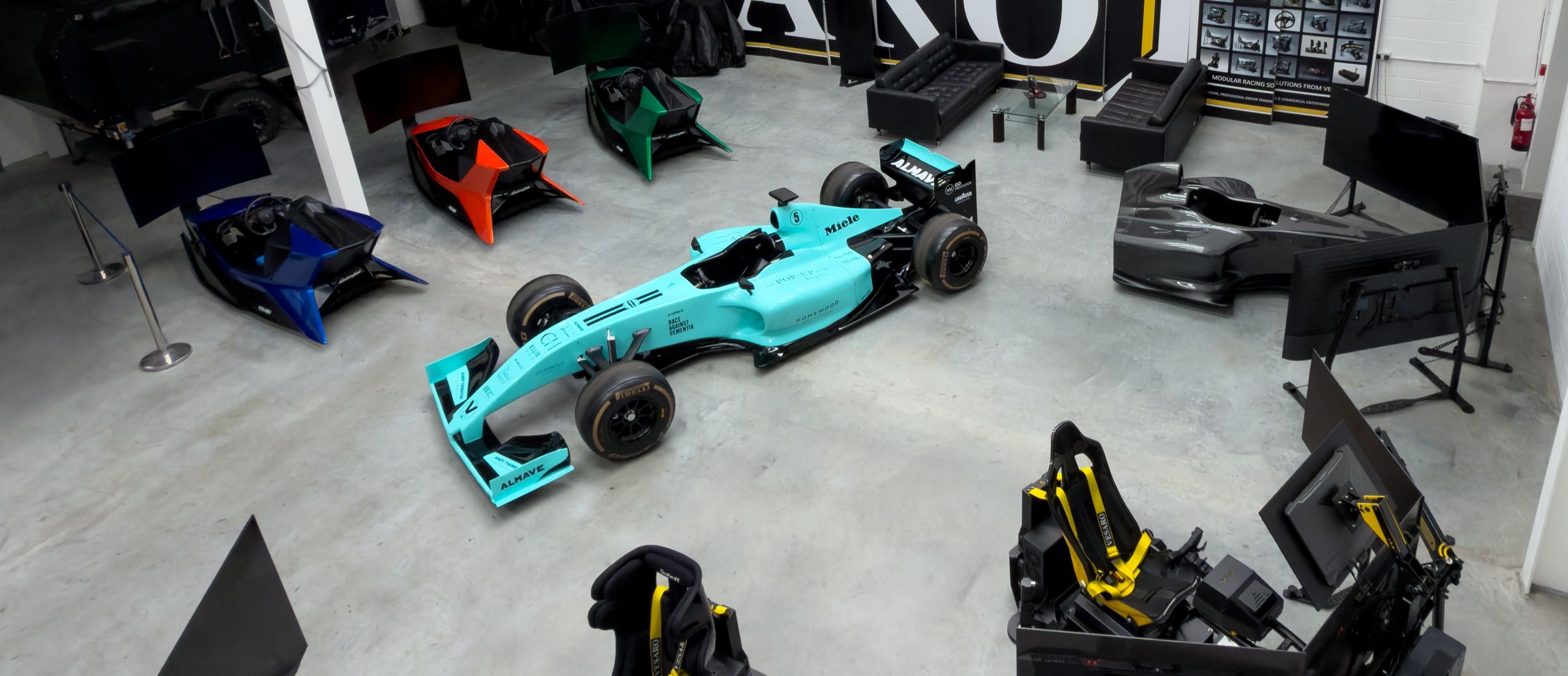 Overhead view of the Vesaro showroom with a full-size F1 simulator centrepiece