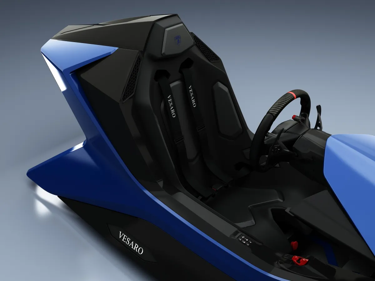 Close-up of the blue Vesaro Lamborghini simulator seat with harness and Vesaro lettering, steering wheel at right