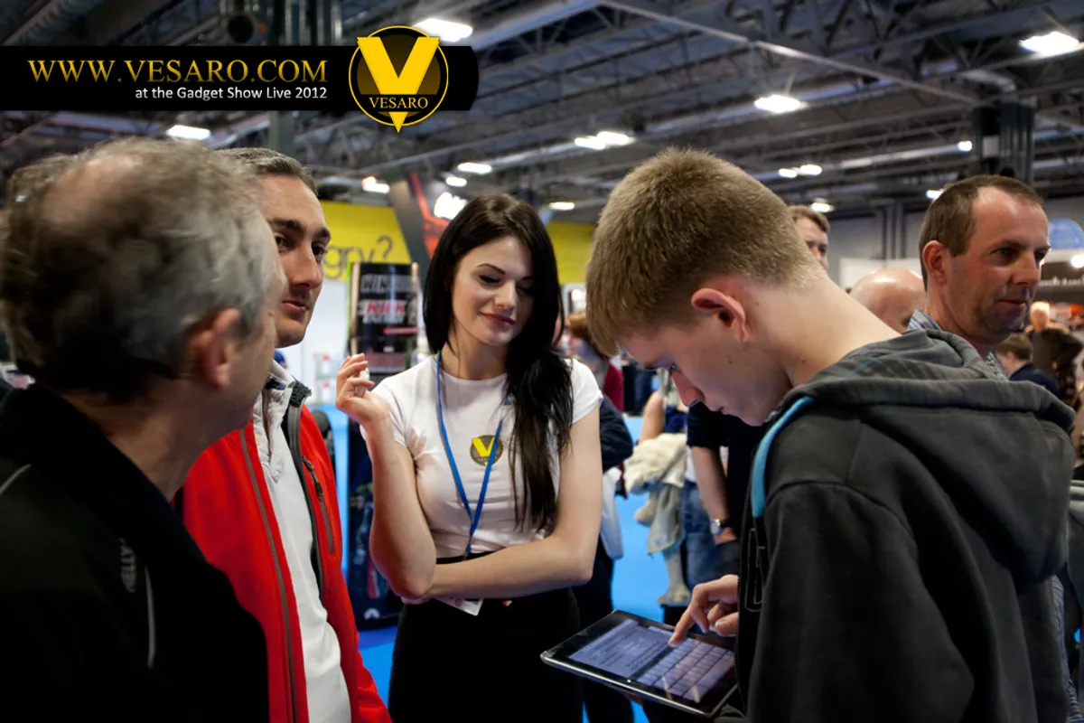 Visitors gathered around a Vesaro stand host holding a tablet at Gadget Show Live 2012
