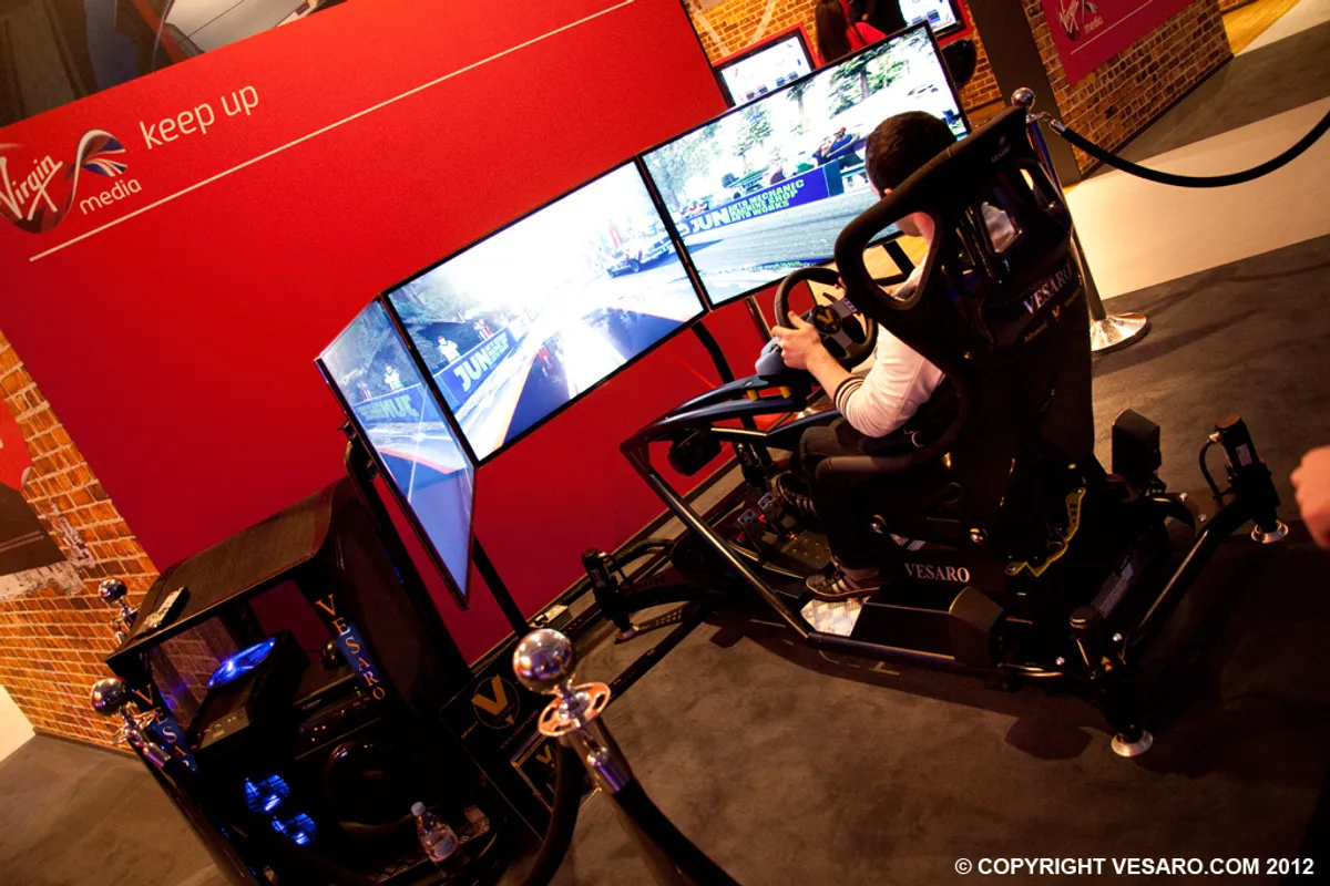 Visitor driving a Vesaro racing simulator with three screens in front of a red Virgin Media backdrop