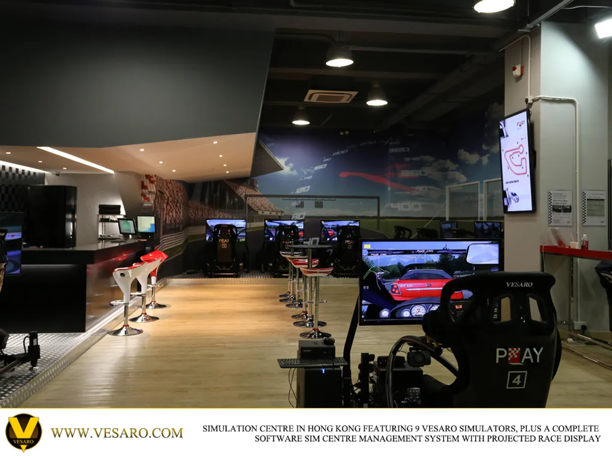 Interior of a sim centre with a bar, stools and a row of Vesaro simulators with monitors under downlights