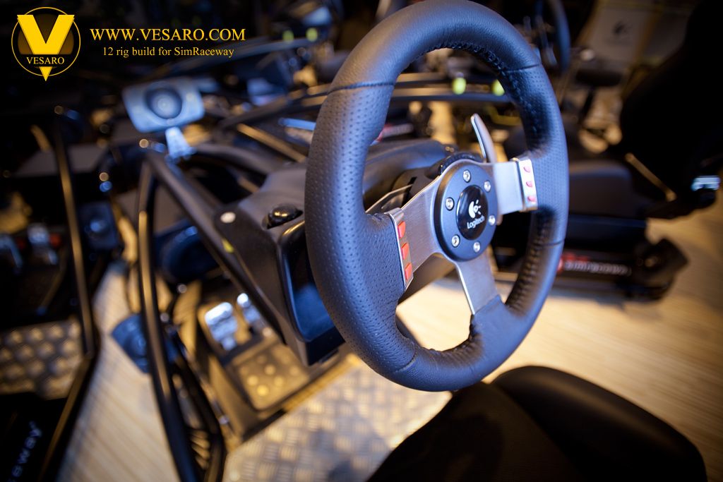 Close-up of a black leather racing wheel on a Vesaro simulator rig with pedals and other rigs behind