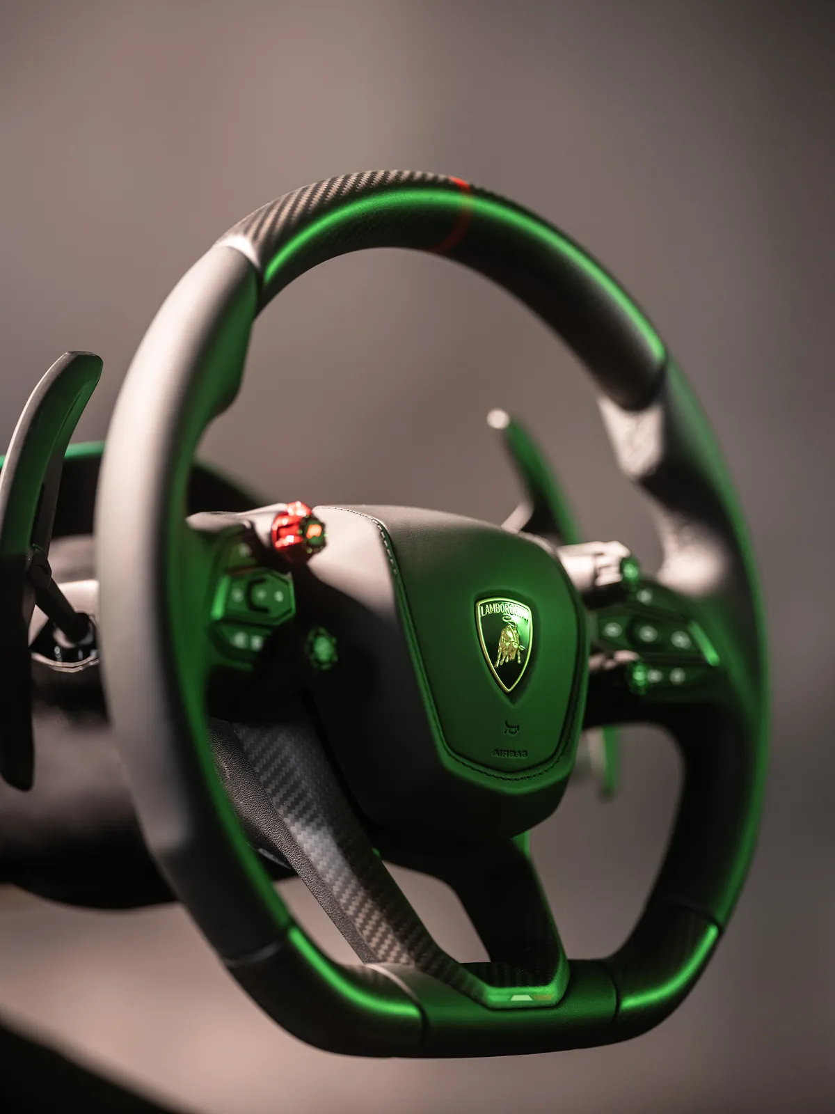 Lamborghini steering wheel with carbon trim, paddle shifters and a green-lit crest in the Vesaro simulator