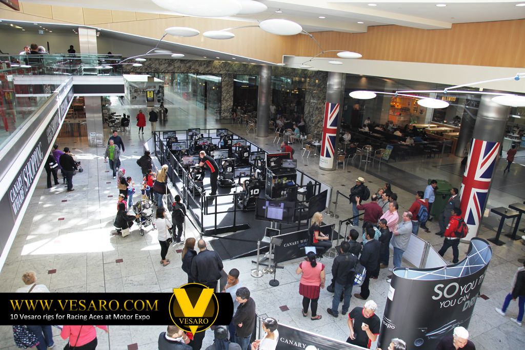 Wide view down into a shopping centre atrium with a roped-off Vesaro simulator area and Union Jack banners