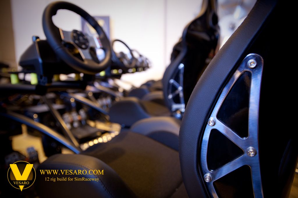 Blurred wheel and pedals on a simulator rig beyond a black bucket seat with a perforated side bolster
