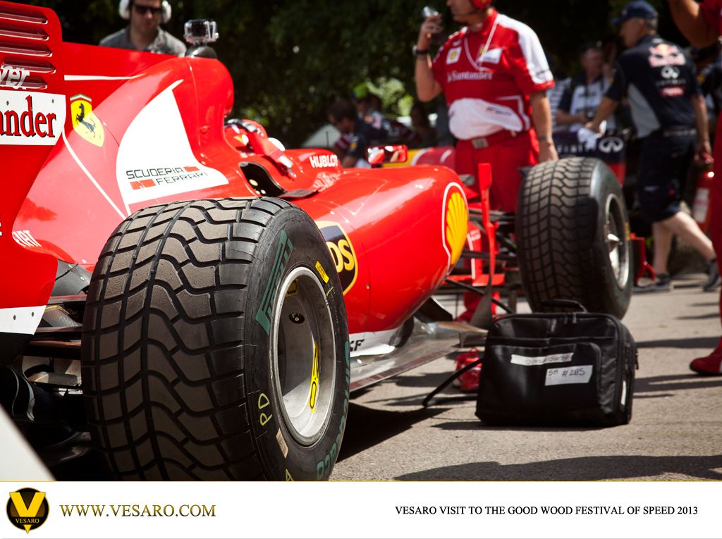 Front-left tyre and nose of a red Ferrari F1 car with crew standing behind at Goodwood