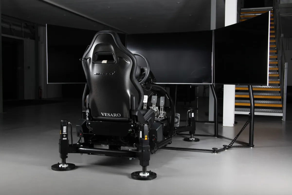 Rear view of a black Vesaro simulator seat on a motion base facing three large screens