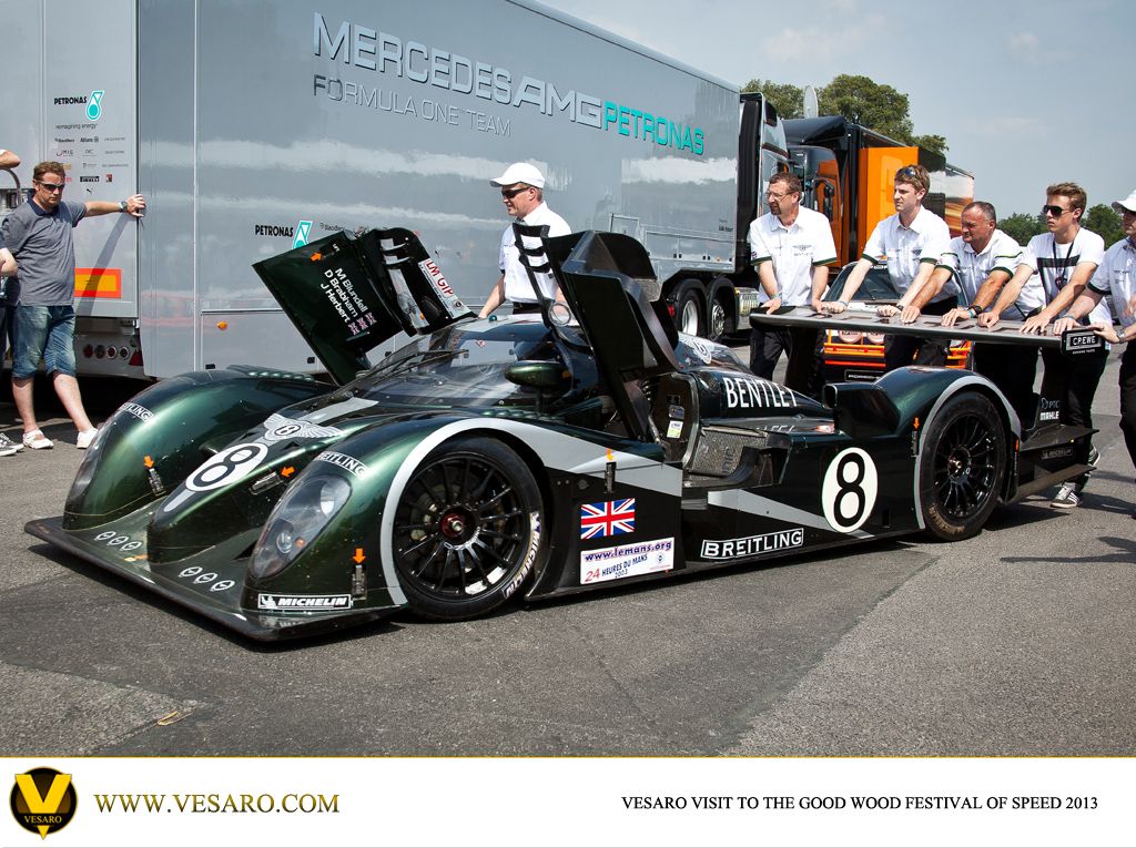 Green Bentley Speed 8 Le Mans prototype with its rear bodywork raised, crew standing behind it