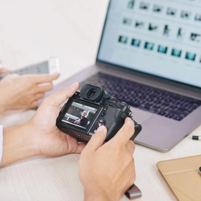 Photographers reviewing images beside a laptop displaying multiple photo thumbnails